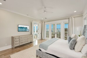 A bedroom with a large bed, a dresser, a ceiling fan, and a view of the outdoors through glass doors. - Endless Summer|Easy Beach Access|Private Pool|Golf Cart (Inlet Beach)