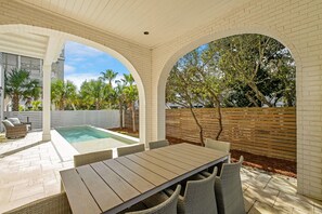 A covered patio with a pool, outdoor seating, and a view of trees and a fence. - Endless Summer|Easy Beach Access|Private Pool|Golf Cart (Inlet Beach)