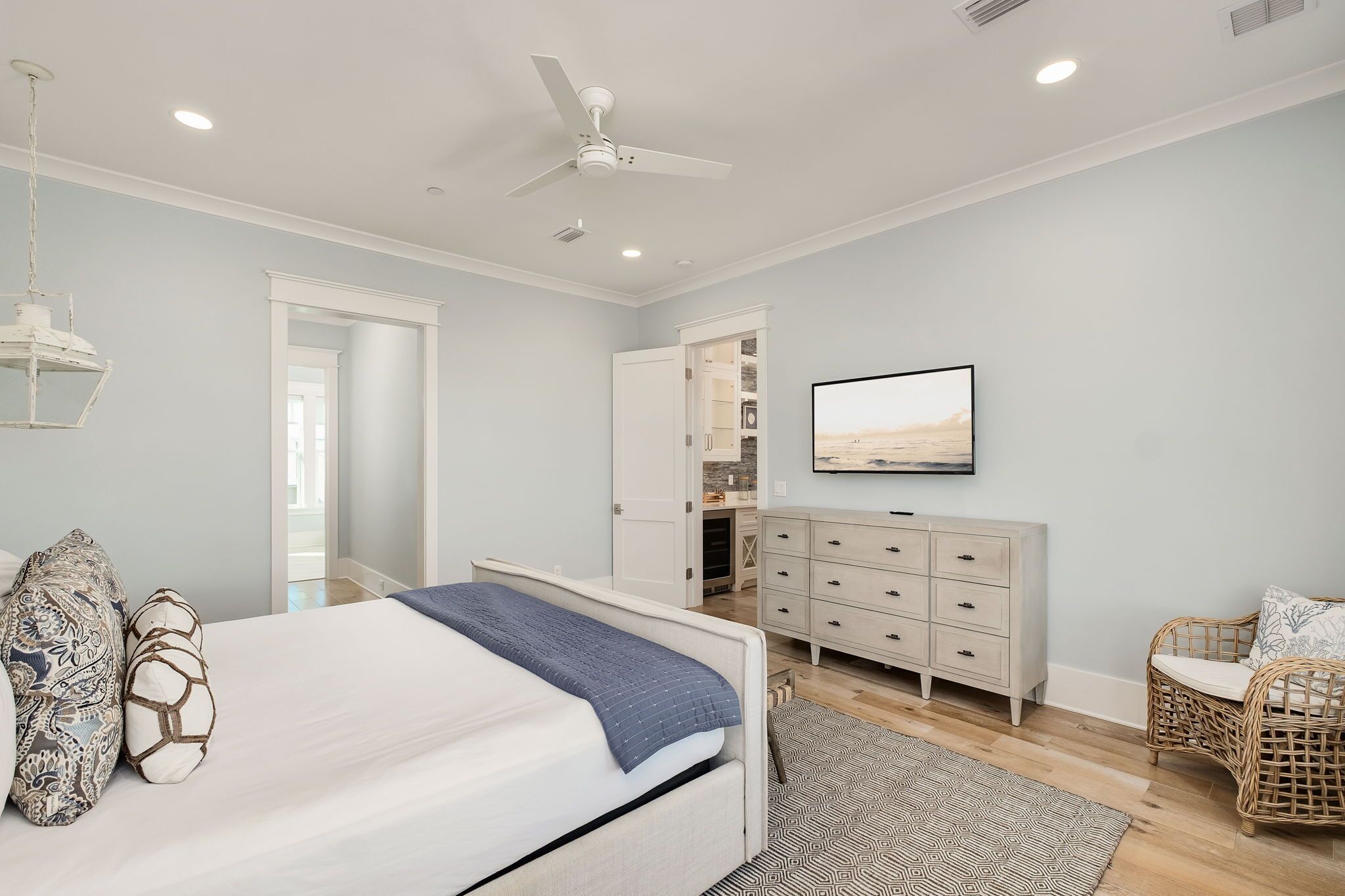 A bedroom with a bed, a dresser, a television, and a ceiling fan.