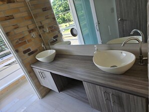 A modern bathroom with two sinks, a mirror, and a view of the outdoors.