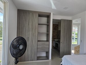 A bedroom with a bed, a wardrobe, and a fan.