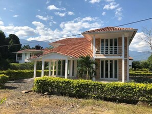 A two-story house with a red-tiled roof, a covered porch, and a well-maintained garden.