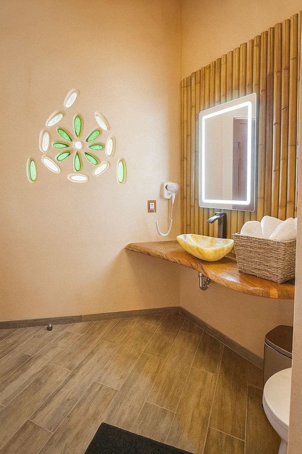 Un baño con tocador de madera, espejo montado en la pared, lámpara decorativa y un inodoro.