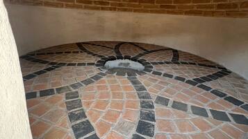 A circular stone-tiled floor with a brick wall and a white pillar.