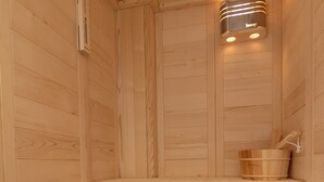 Eine Holzsauna mit Bänken und einem Eimer.