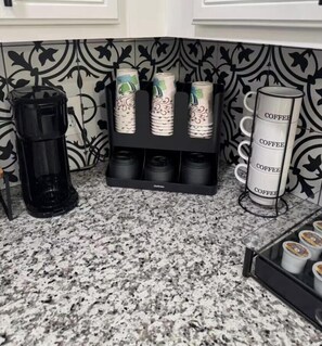 Una cocina con cafetera, una estación de café con tazas múltiples y un dispensador de café.