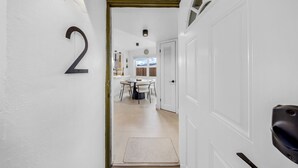 A hallway with a number '2' sign, leading to a dining area with a round table and chairs.