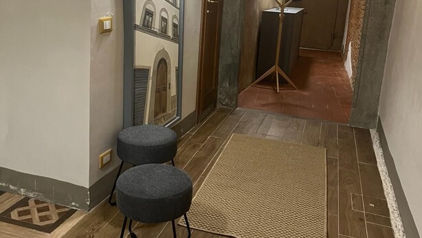 Un couloir doté d’un plancher en bois, d’un miroir, d’une lampe et d’une petite table.