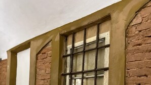 Un bâtiment en briques avec une fenêtre ornée d’un motif quadrillé et d’un vitrage blanc.
