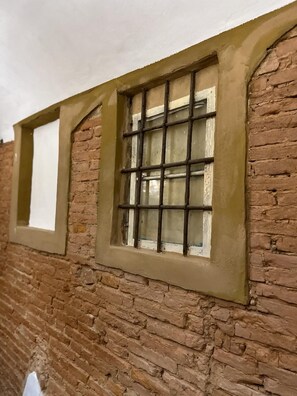 Ein Backsteinhaus mit einem Fenster, das ein Rastermuster und eine weiße Scheibe aufweist.