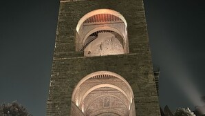 Une haute tour de pierre, dotée de plusieurs arcades et d’un escalier menant à son sommet.