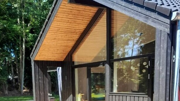 A modern building with large windows, a wooden deck, and a door leading to an outdoor area. - 4 Star Holiday Home in Gilleleje (Gilleleje)