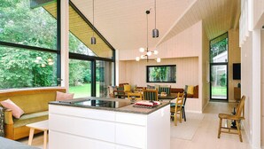 A modern kitchen with a large island, dining area, and large windows offering a view of the outdoors. - 4 Star Holiday Home in Gilleleje (Gilleleje)