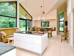 A modern kitchen with a large island, dining area, and large windows offering a view of the outdoors. - 4 Star Holiday Home in Gilleleje (Gilleleje)
