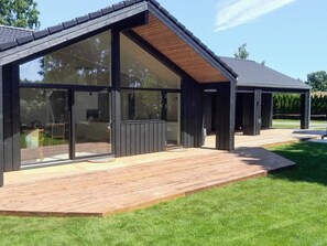 A modern building with large glass windows, a wooden deck, and a covered outdoor area. - 4 Star Holiday Home in Gilleleje (Gilleleje)