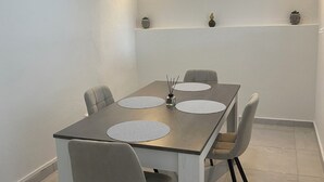 Et spiseområde med et rektangulært bord, fire stole og en loftsvifte.