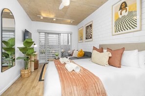 Moderni hotellihuone, jossa on suuri sänky, sohva, ruokapöytä ja suuri ikkuna.