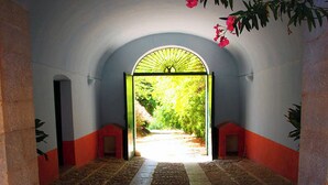 An arched doorway leading to a garden, with a patterned floor and red and white walls. - Masseria dei Paternostro - Private Sicilian Estate with Pool near Corleone (Corleone)