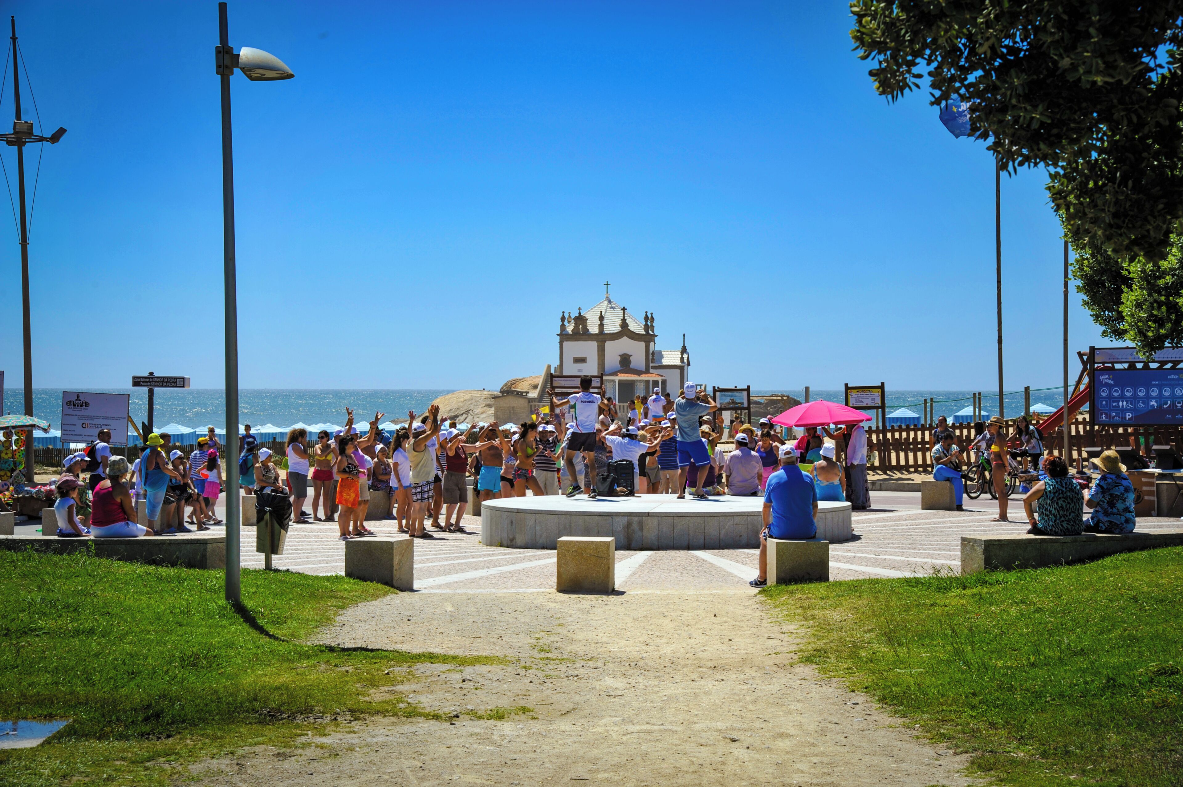 Une place publique avec une scène centrale, une église en arrière-plan et une foule de personnes.