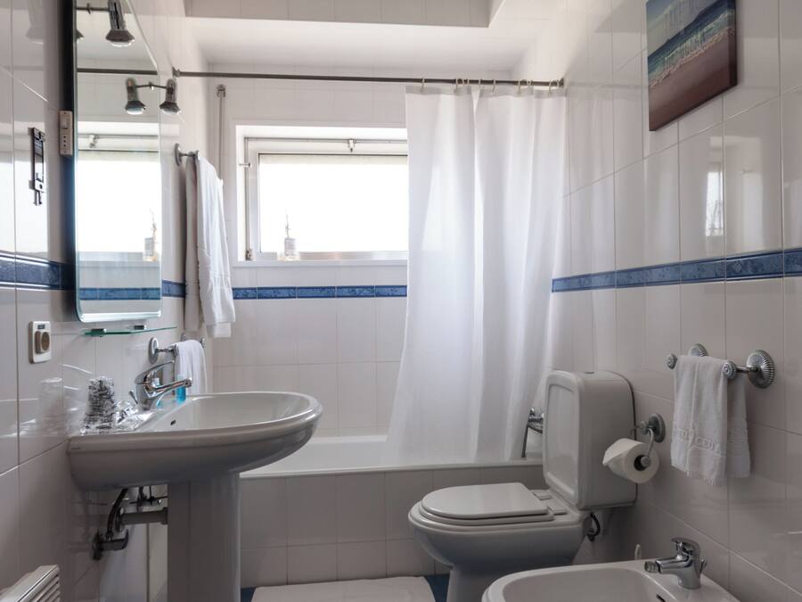 A bathroom with a sink, bidet, toilet, and bathtub.