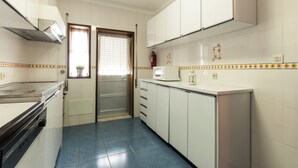 A kitchen with white cabinets, a microwave, and a sink. - Apartamentos Turísticos Céu Azul (Vila Nova de Gaia)