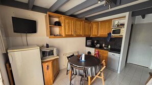 Une cuisine compacte avec des meubles en bois, un four à micro-ondes encastré, un grille-pain et une table avec des chaises.