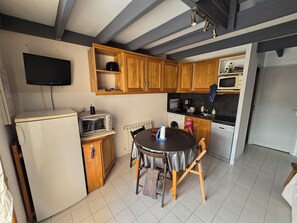 Une cuisine compacte avec des meubles en bois, un four à micro-ondes encastré, un grille-pain et une table avec des chaises.
