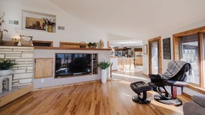 Ein geräumiges Wohnzimmer mit Kamin, einem bequemen Ledersessel und einem Essbereich im Hintergrund.
