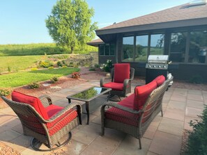 An outdoor patio with wicker furniture and a grill.