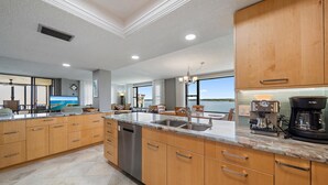 Una cocina moderna con armarios de madera, encimera de mármol y vista al agua.