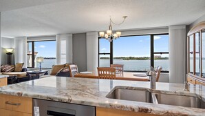 Una cocina moderna con encimera de mármol, lavavajillas integrado y un amplio ventanal con vistas al agua.