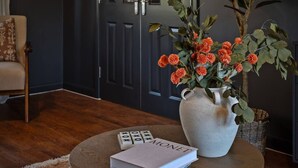 A living room with a round coffee table, a vase with orange flowers, and a book titled "MONET". - The Seven Residence - near Bicester village (Bicester)