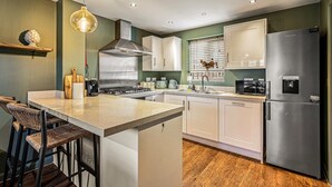 A modern kitchen with a central island, white cabinets, a stainless steel refrigerator, and a hanging light fixture. - The Seven Residence - near Bicester village (Bicester)