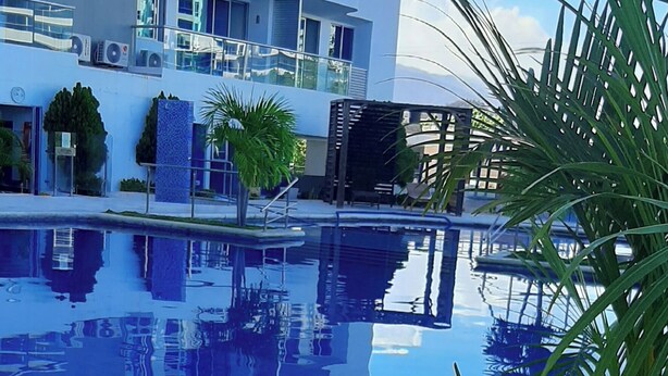 A modern hotel with a swimming pool, balconies, and lush greenery. - Santa Marta, Colombia—Apartment in Rodadero Sur for 1–6 people, 2 bedrooms, 2 bathrooms (Gaira)
