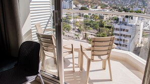 A balcony with two chairs and a table, overlooking a cityscape with buildings and mountains. - Santa Marta, Colombia—Apartment in Rodadero Sur for 1–6 people, 2 bedrooms, 2 bathrooms (Gaira)