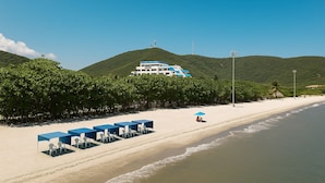 A beach with a row of blue tables and chairs, a building with a blue and white facade, and a clear sky. - Santa Marta, Colombia—Apartment in Rodadero Sur for 1–6 people, 2 bedrooms, 2 bathrooms (Gaira)