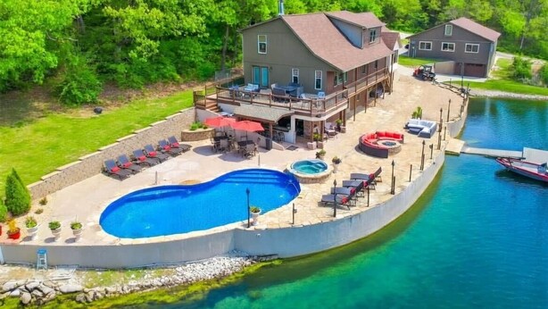 Una propiedad frente al lago con piscina, mobiliario de exterior y un muelle.