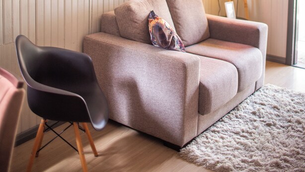 En moderne stue med en beige sofa, en sort lænestol og en gulvlampe.