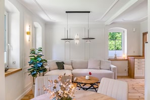 Ein modernes Wohnzimmer mit einer Eckcouch, einem runden Holztisch und einem Topf mit einer Pflanze.
