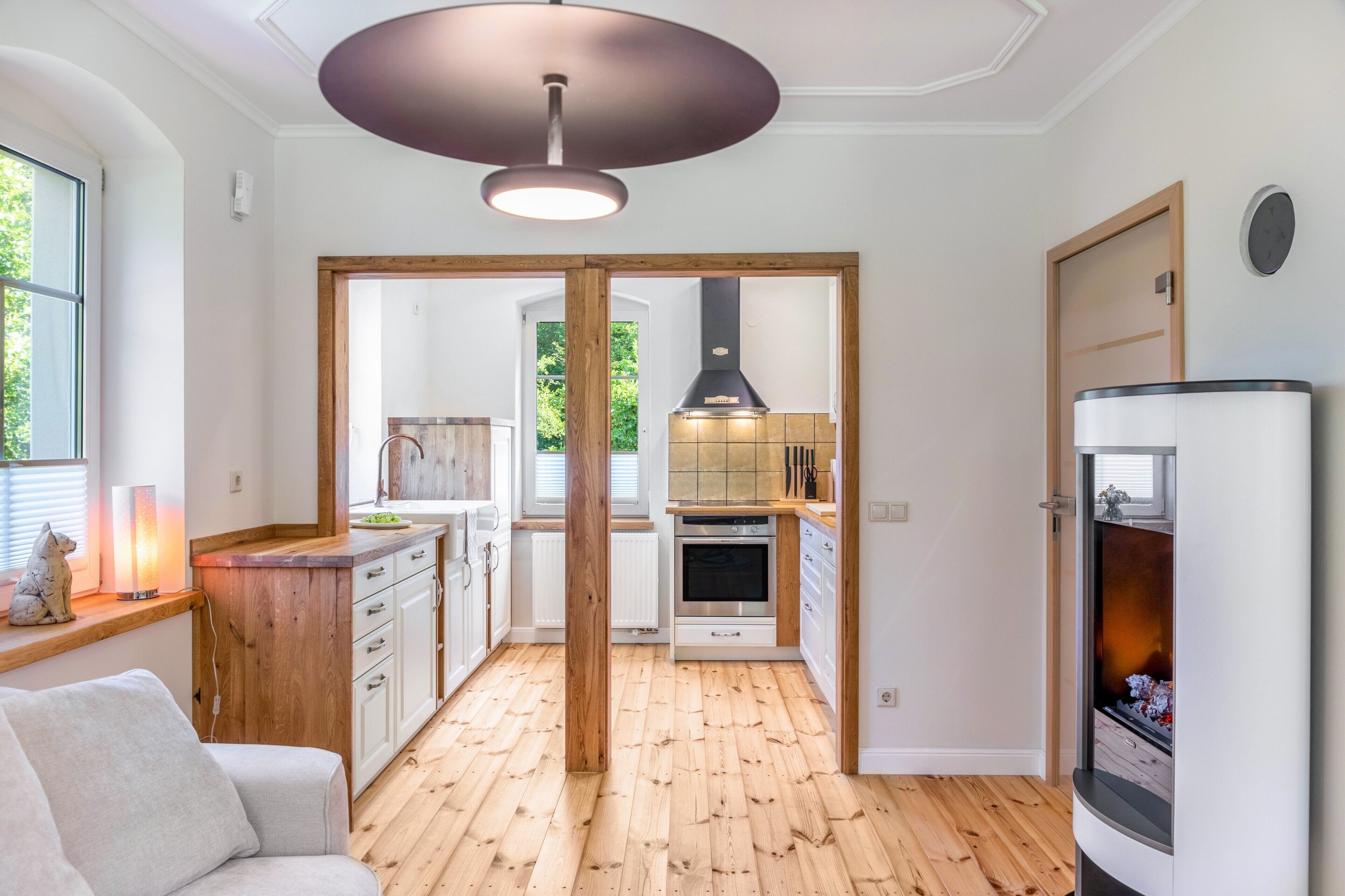 Eine moderne Küche mit Holzboden, weißen Schränken und einem eingebauten Backofen.