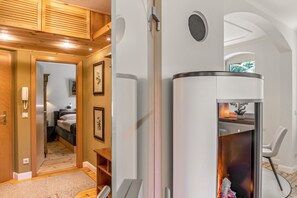 Habitació amb sostre de fusta, una llar de foc, un llit amb capçalera i una porta que dona a una altra habitació.