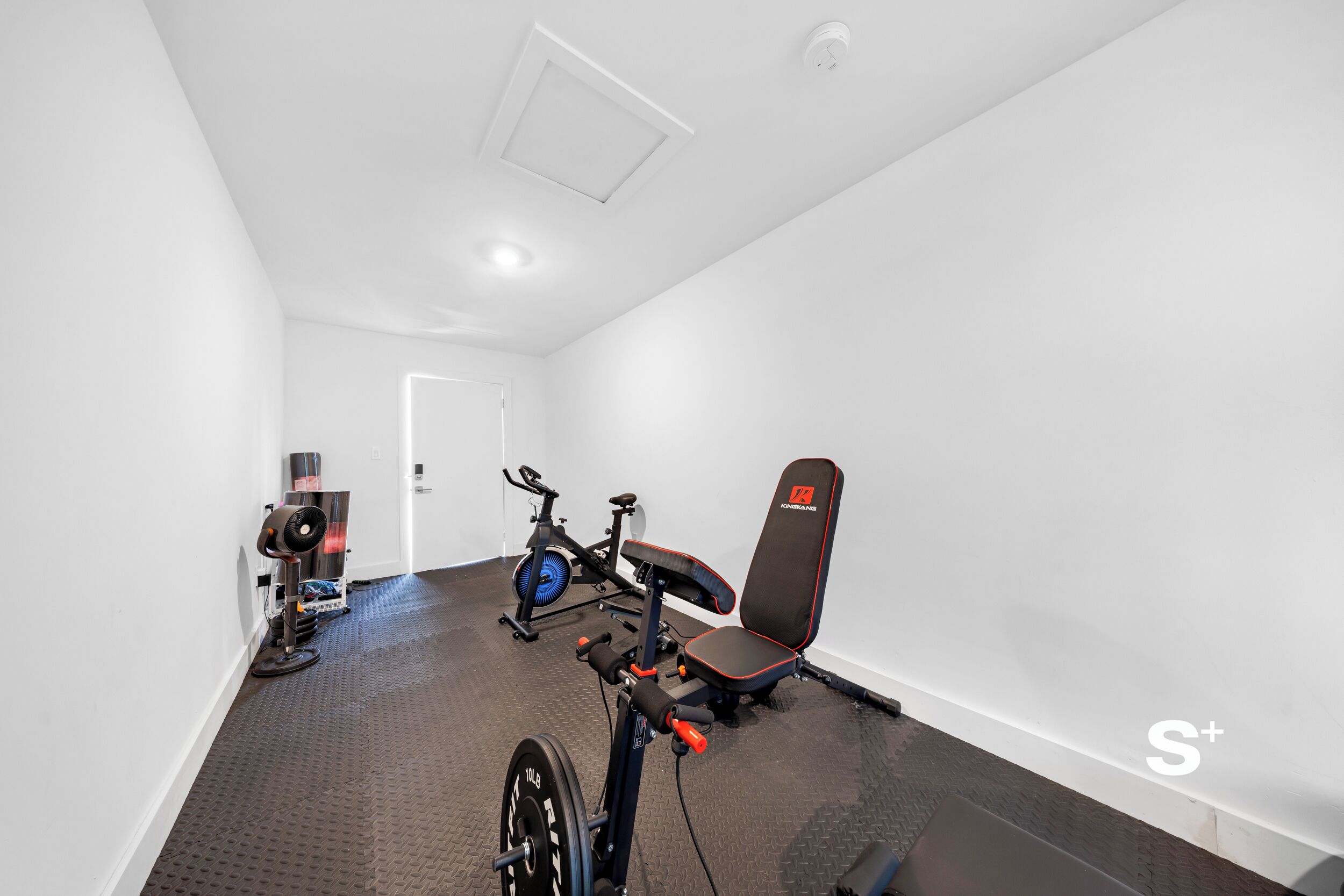 A gym with a weight bench, exercise bike, and a wall-mounted punching bag.
