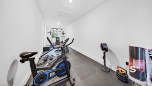 Ett gym med konditionsmaskiner, styrketräningsmaskiner och en boxningssäck.