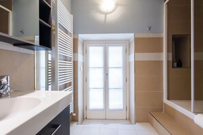 A bathroom with a white sink, a mirror, a shower, and a door with frosted glass panels. - Casa Rosa - hidden Garden with lake view (Fiumelatte)