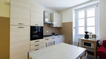 A modern kitchen with a dining table, chairs, a stove, oven, microwave, and cabinets.