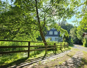 Ein ländlicher Pfad führt zu einem Haus, umgeben von üppigem Grün und Bäumen.