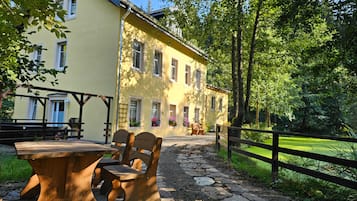Un bâtiment jaune avec un chemin de pierre menant à un banc et une table en bois.