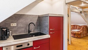 Eine kleine Küche mit Spüle, Kaffeemaschine und einem roten Schrank.
