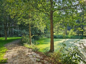 A stone pathway leading through a lush garden with trees and greenery. - Apartment "Schwarzmühle 3" with Lake View, Private Garden and Wi-Fi (Börnichen/Erzgeb.)
