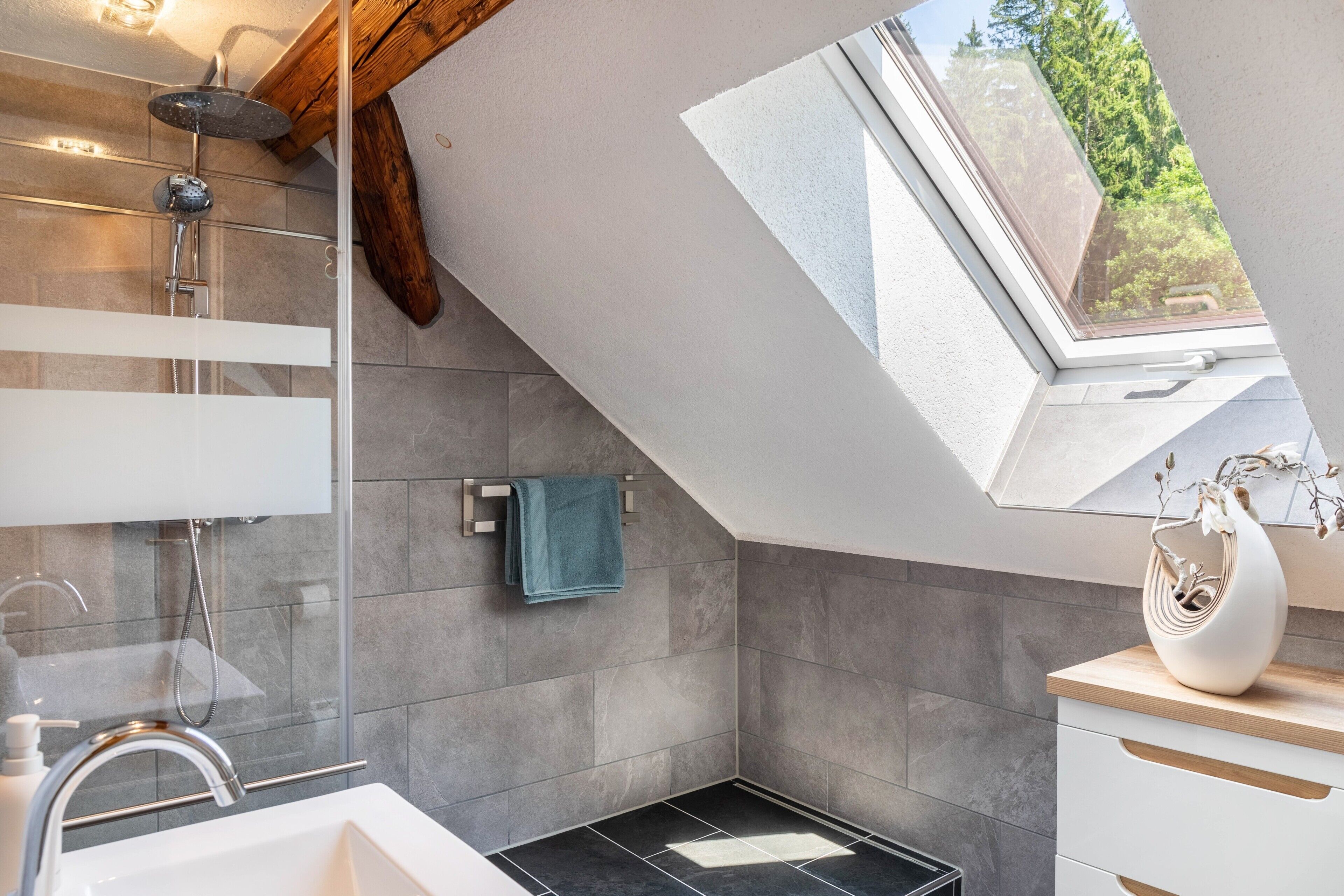 A modern bathroom with a skylight, a shower, and a sink.